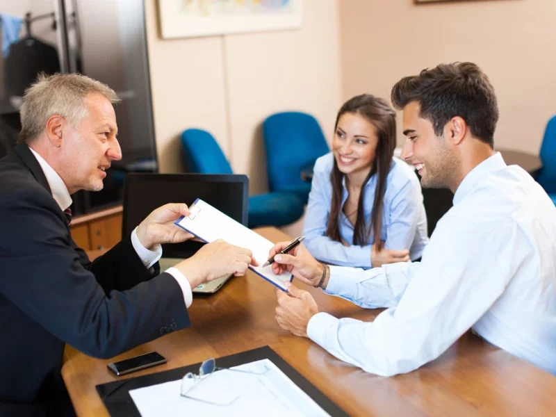 Advogado sentado em sua mesa, com um casal ao seu lado assinando um contrato de união estável